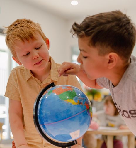 Children at a childcare centre examining a globe, exploring geography and learning about the world as part of early childhood education.