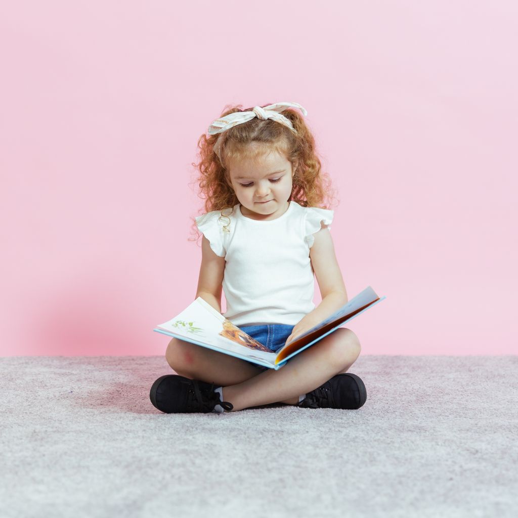 A child reading a book at a childcare centre, engaging in early learning activities that promote literacy and child development.