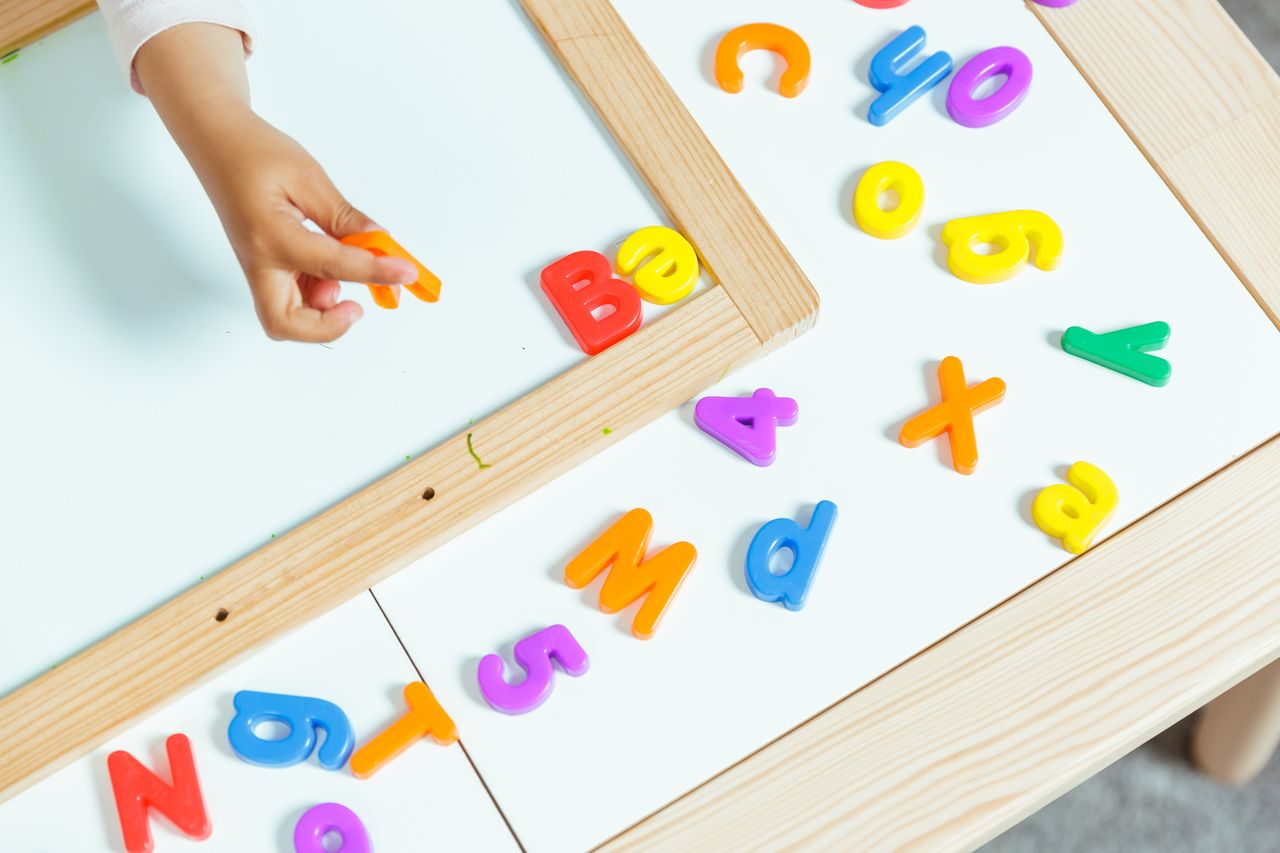 A child playing with alphabet blocks at a childcare centre, learning letters and developing early literacy skills.