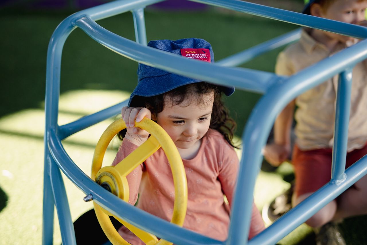 A child playing with a toy car at a childcare centre, engaging in imaginative play that supports child development and early learning.