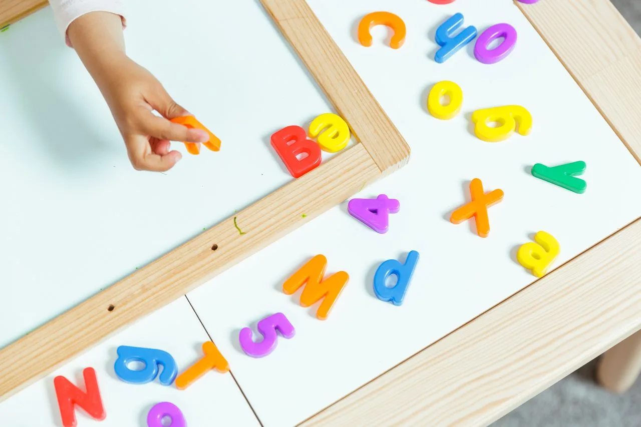 A child arranging letter blocks at the child care centre, fostering literacy through engaging childcare services